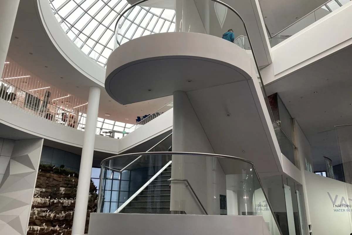 Escalier hélicoïdal blanc dans un atrium éclairé par une verrière