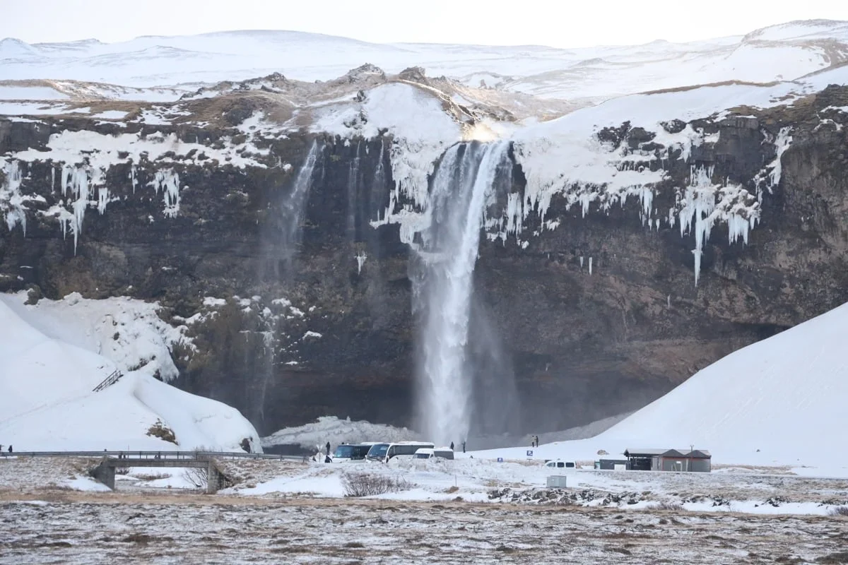 Grande cascade tombant d'une falaise rocheuse enneigée en hiver
