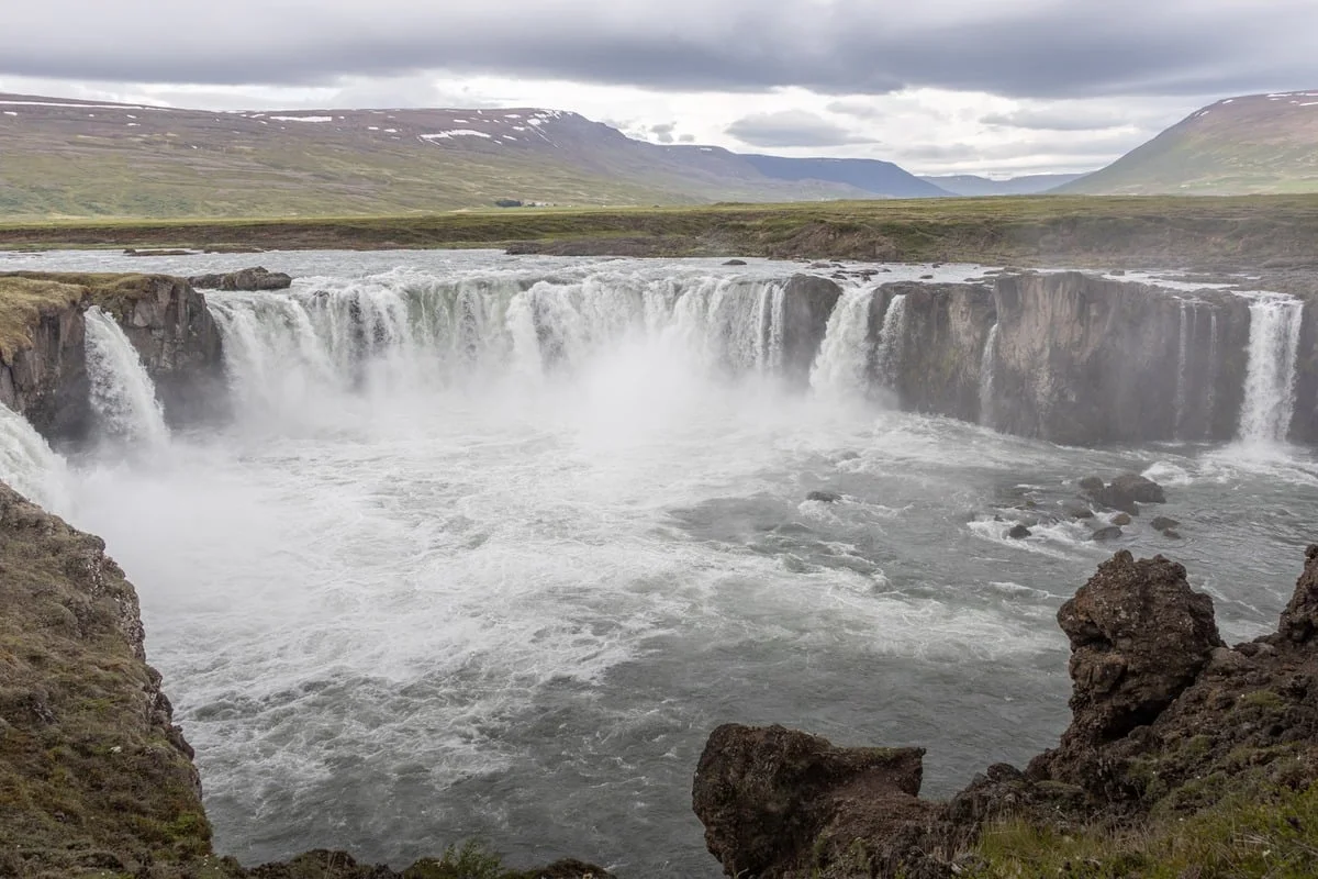 Grande cascade en fer à cheval avec brume et roches volcaniques au premier plan
