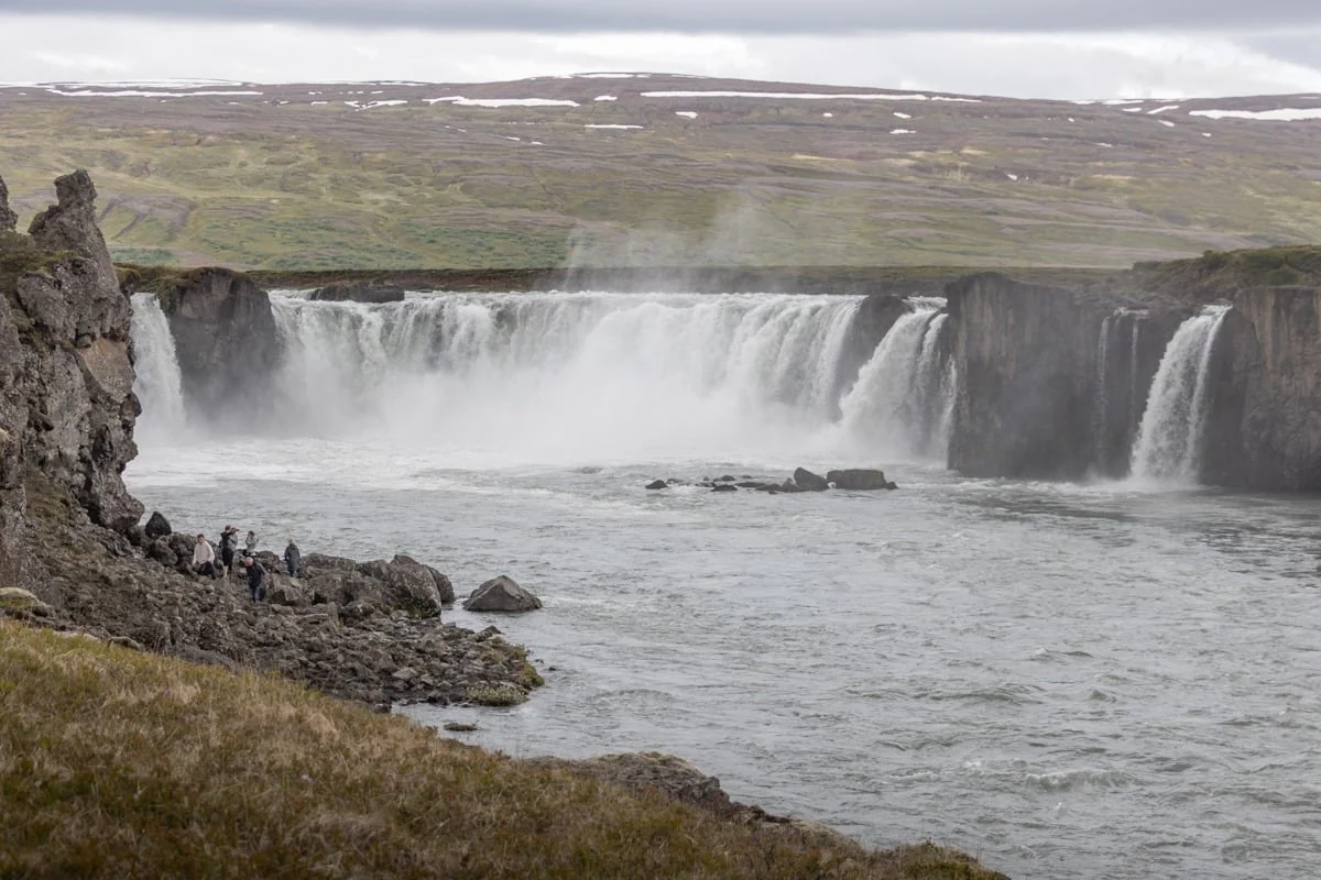 Large cascade en fer à cheval avec visiteurs sur les rochers au premier plan