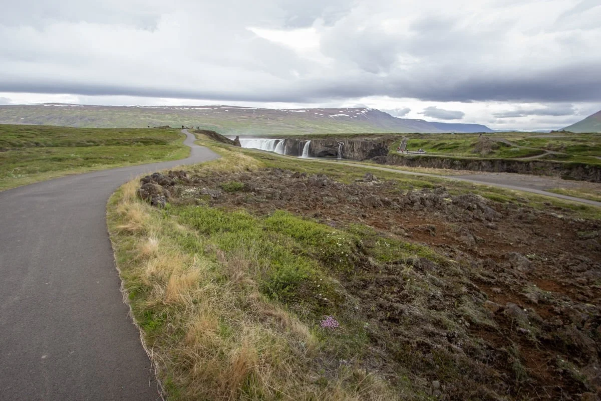 Chemin sinueux longeant une cascade dans un paysage volcanique verdoyant
