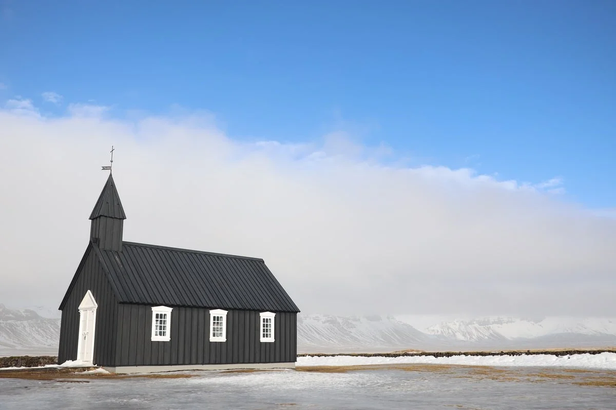 Eglise en bois noir aux fenêtres blanches entourée de neige