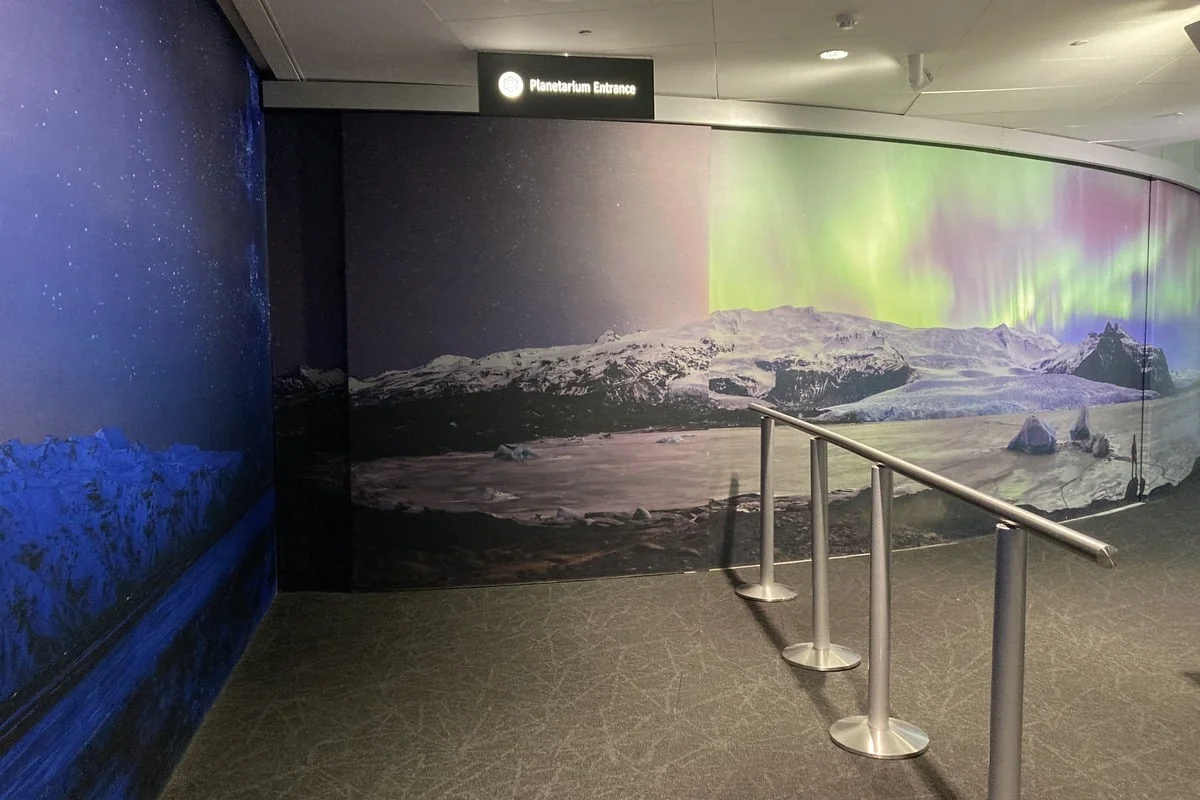 Couloir d'entrée d'un planétarium avec fresque murale d'aurores boréales