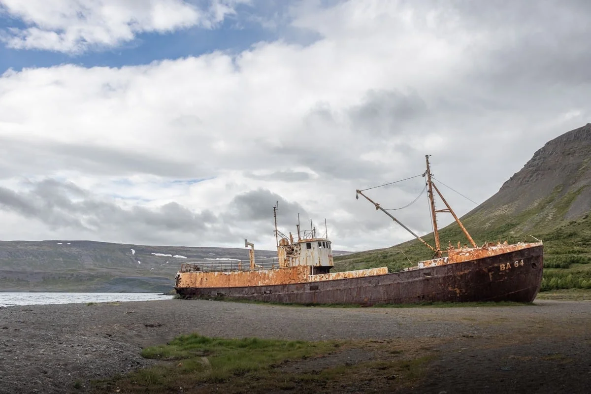 Épave de bateau rouillé échoué sur une plage de galets