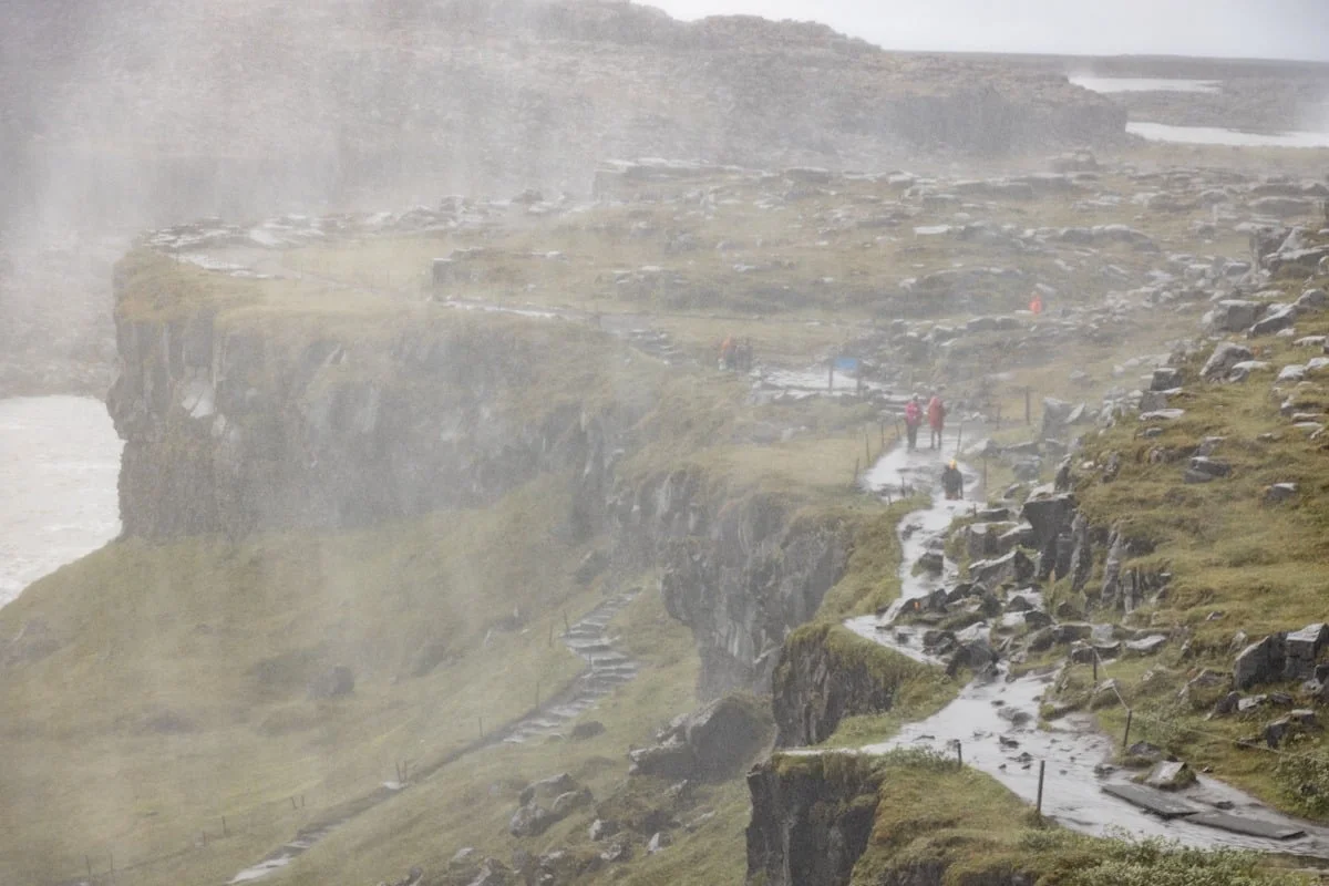Visiteurs sur sentier de falaises sous brume dense