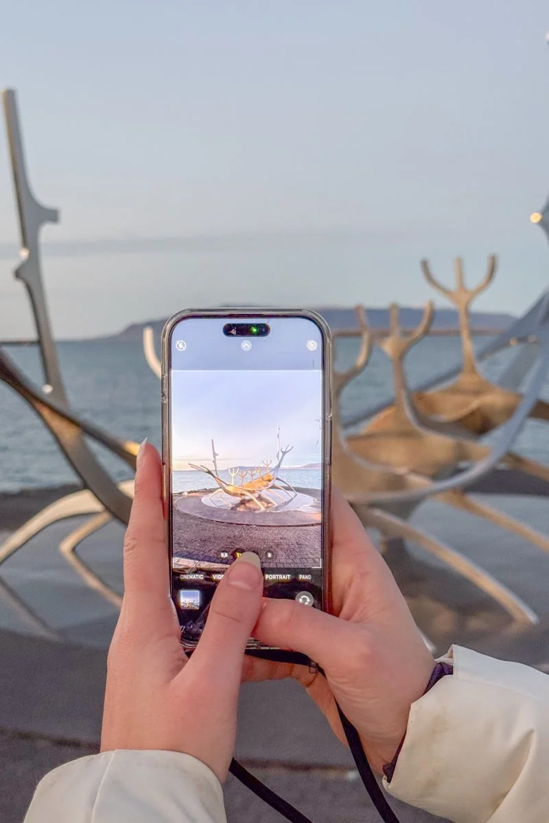 Mains tenant un smartphone photographiant le Voyageur du Soleil