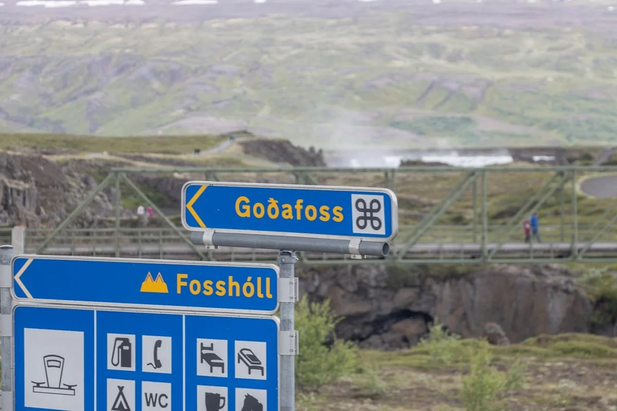 Panneaux de signalisation bleus indiquant une cascade et un pont suspendu