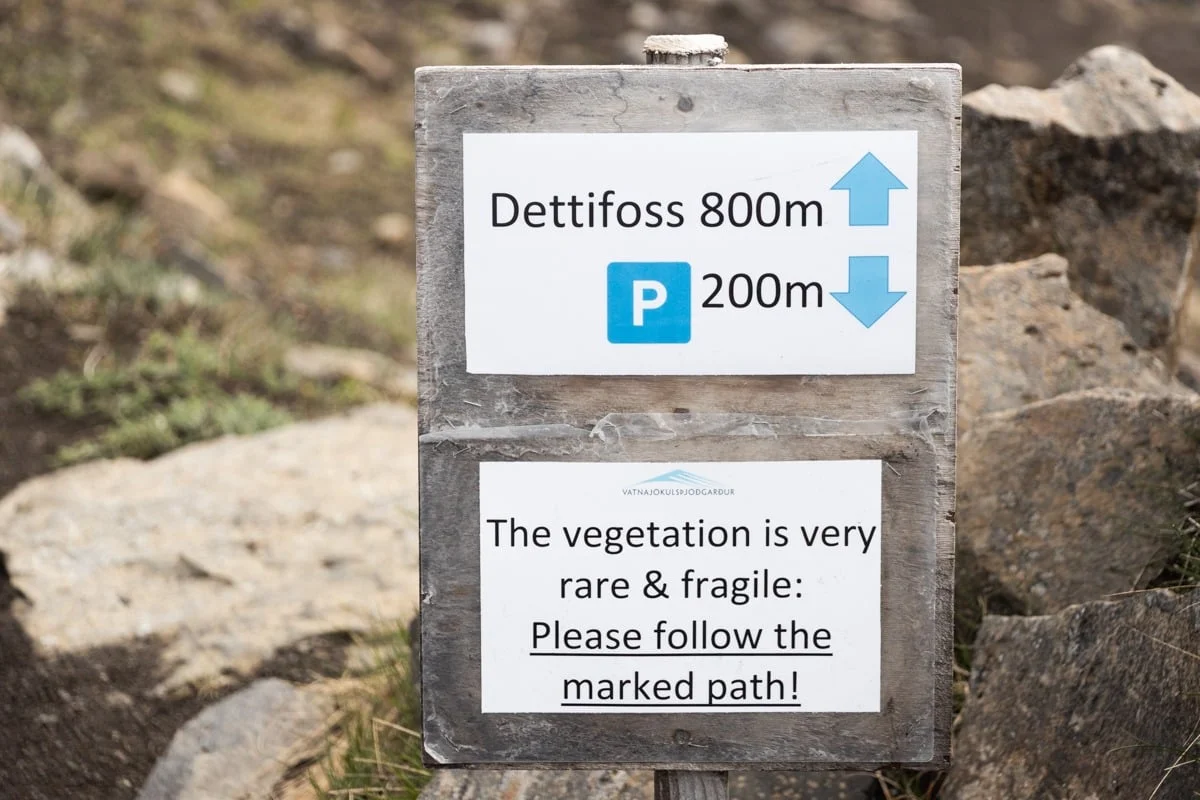 Panneau en bois indiquant la cascade à 800 mètres et un parking