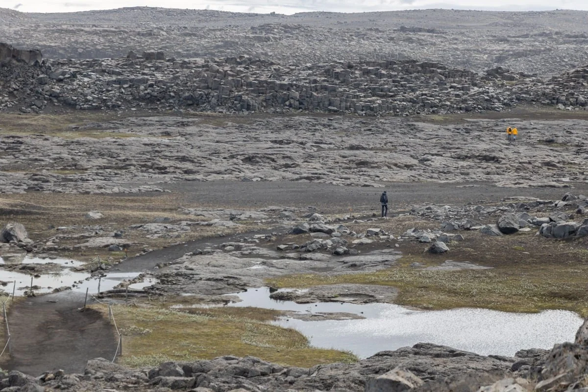 Deux randonneurs traversant un paysage rocheux volcanique