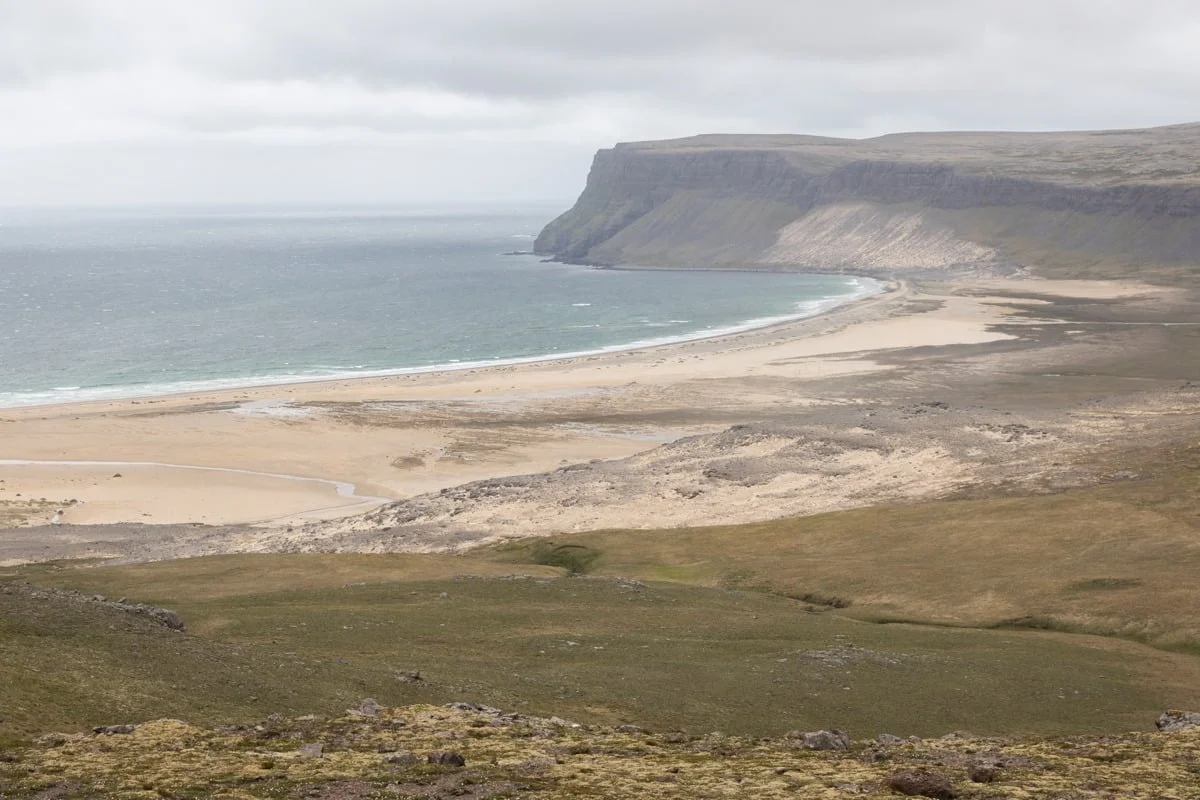 Vaste plage de sable longeant des falaises