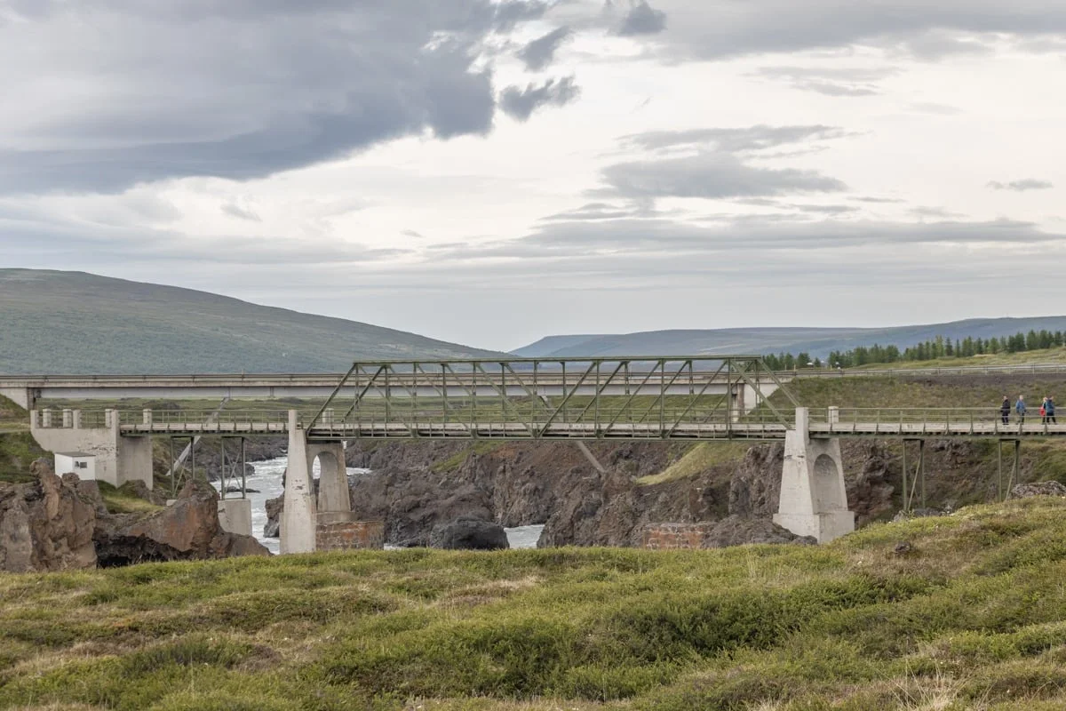 Pont métallique enjambant une gorge rocheuse avec végétation verdoyante