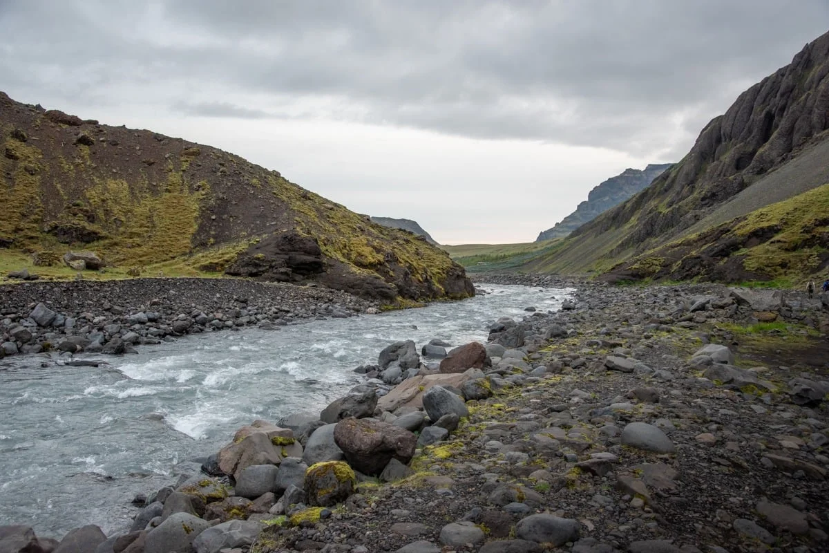 Rivière serpentant entre des rochers volcaniques et des collines verdoyantes