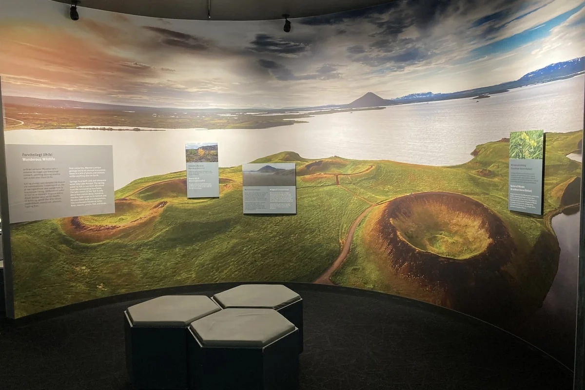 Salle d'exposition avec fresque panoramique de cratères volcaniques et poufs