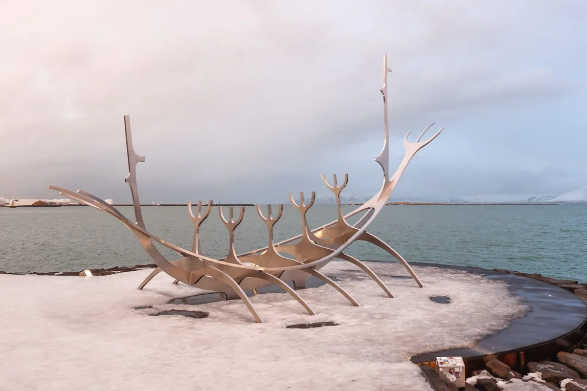Grande sculpture en acier en forme de drakkar viking sous la neige au bord de l'eau
