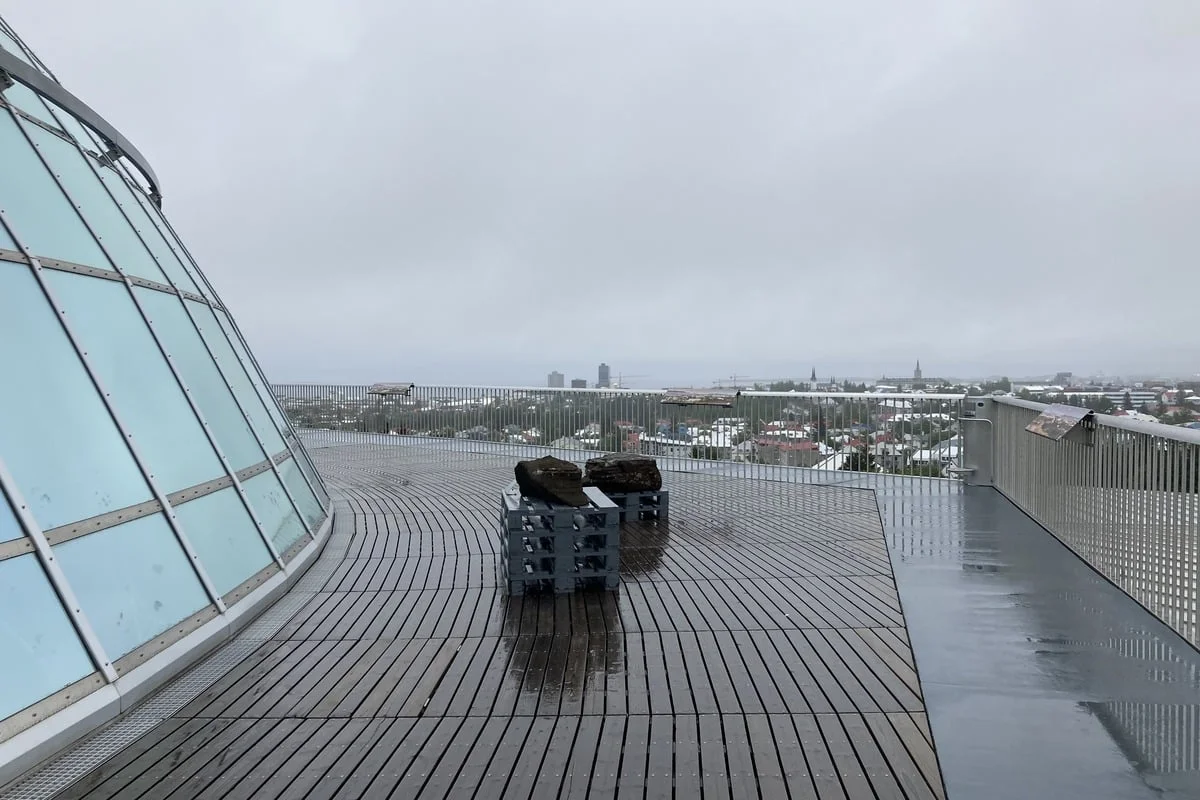 Terrasse en bois mouillée avec rochers volcaniques et vue urbaine