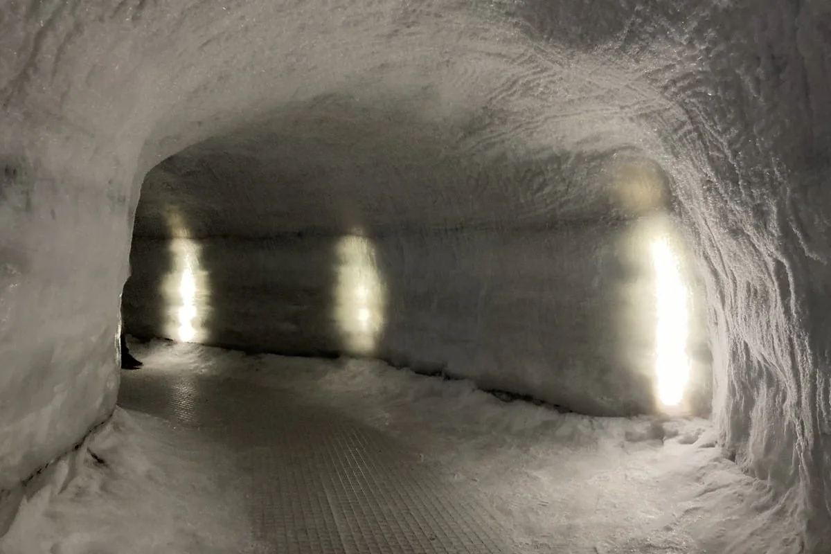 Faux couloir creusé dans la glace éclairé par des spots lumineux au sol