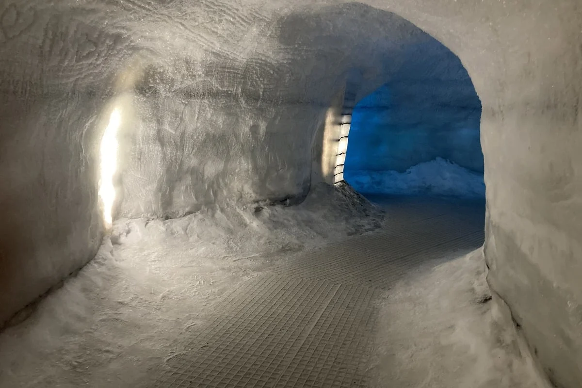Faux couloir creusé dans la neige avec ouverture lumineuse bleue au fond