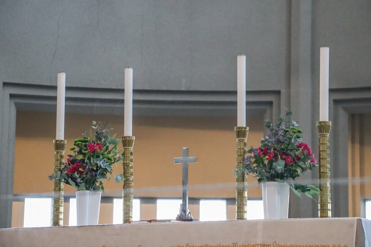 Autel d'église avec bougies, croix argentée et bouquets de fleurs