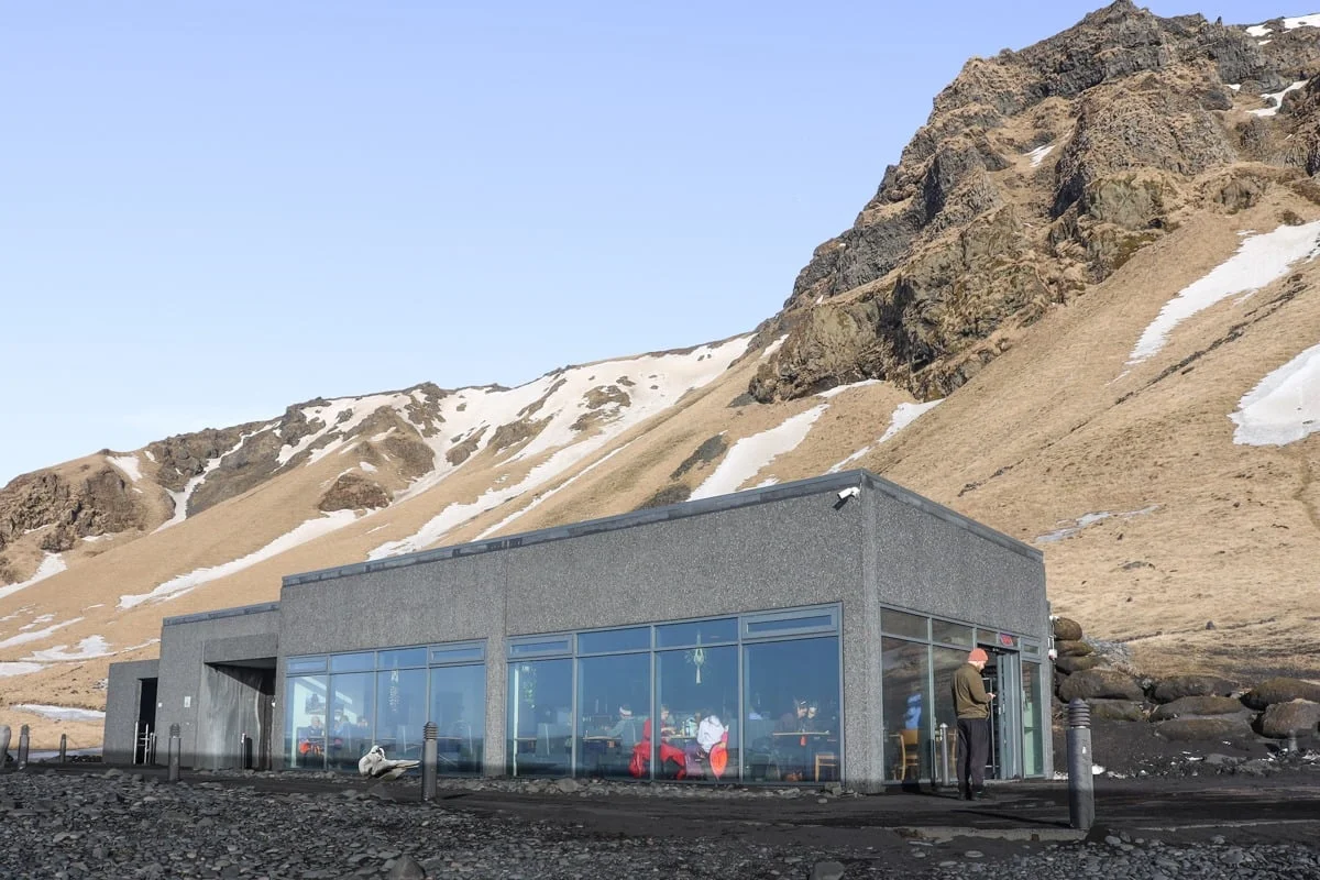Cafétéria moderne en verre et béton au pied d'une montagne enneigée