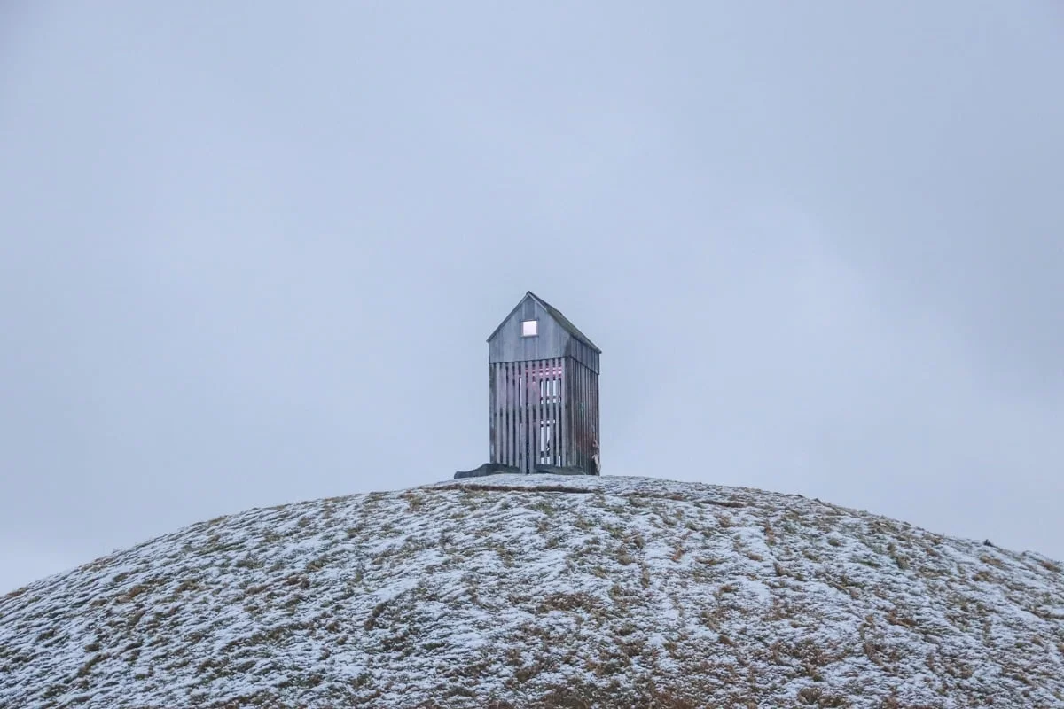 Petite cabane en bois au sommet d'un monticule enneigé