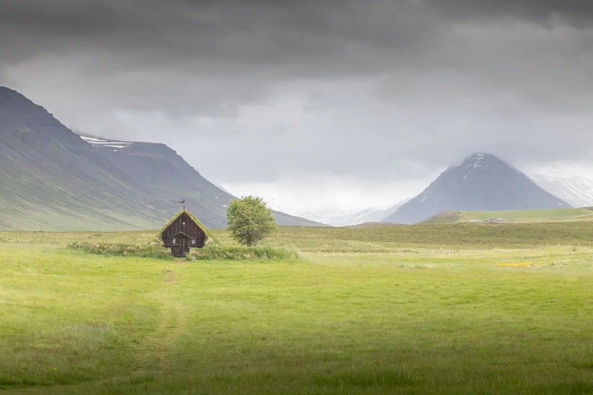 Petite église au milieu d'une vaste prairie verte sous ciel nuageux