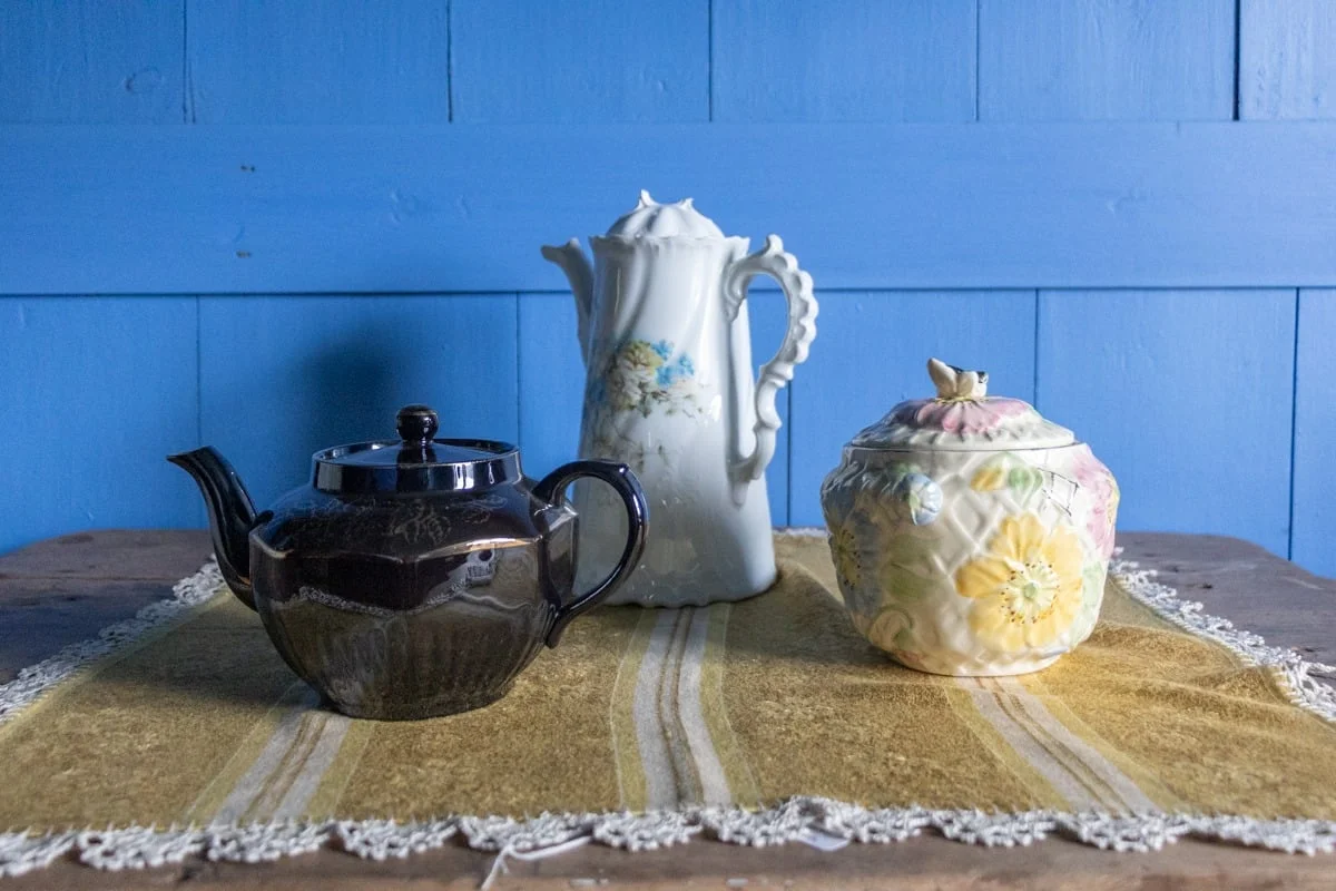 Trois pièces de céramique vintage posées sur une nappe dorée à franges