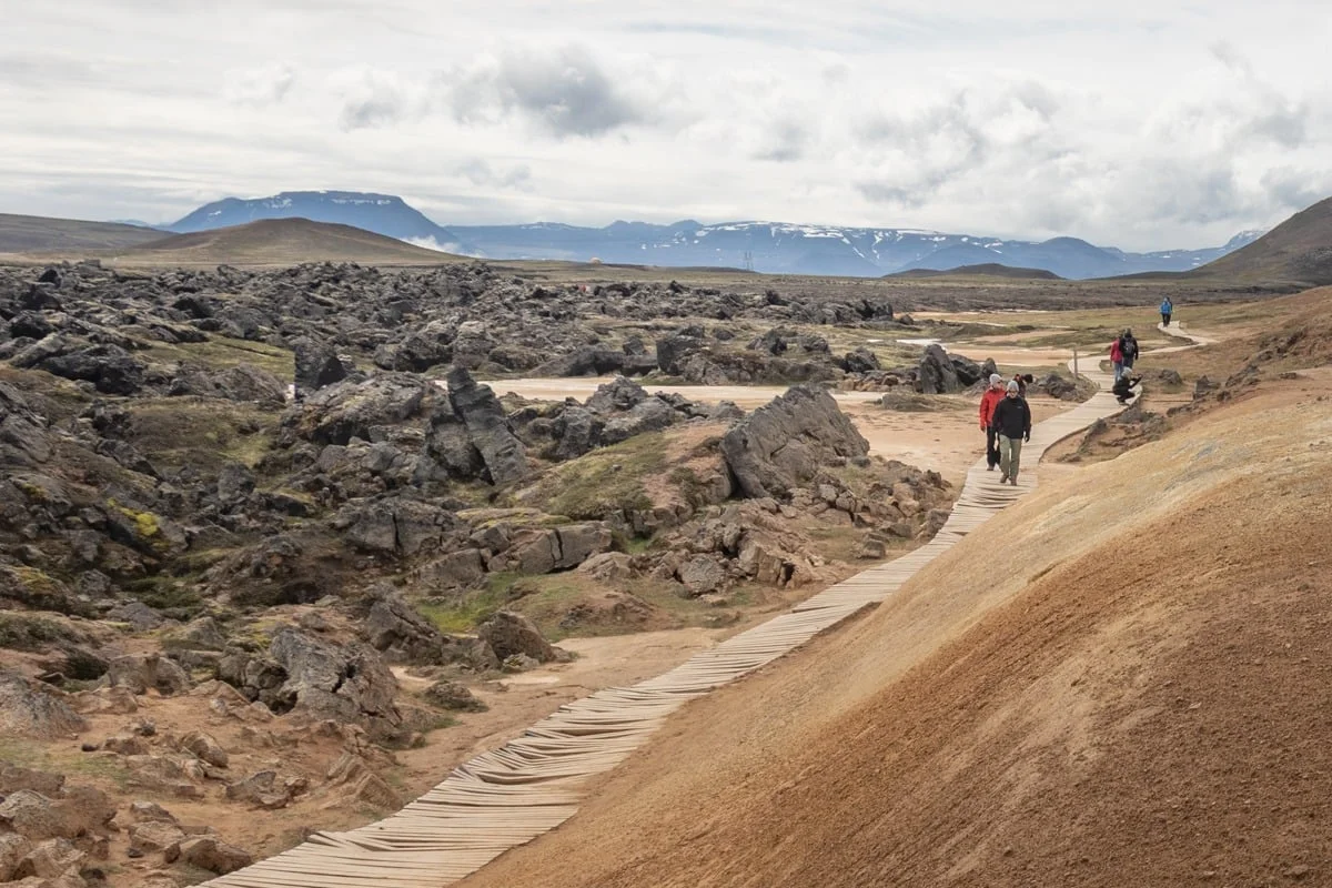 Promeneurs sur un sentier en bois au milieu d'un champ de lave volcanique