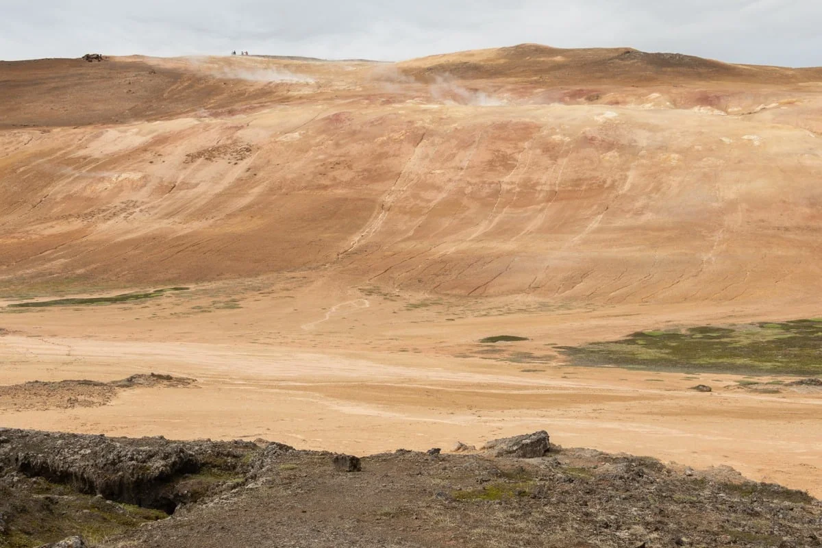 Collines volcaniques ocre avec fumerolles et végétation clairsemée