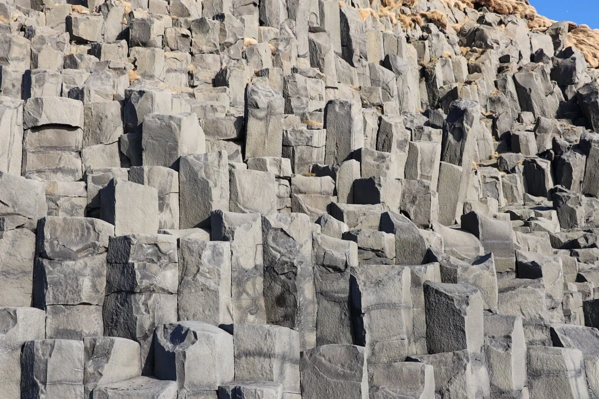 Colonnes de basalte gris formant une falaise géométrique imposante