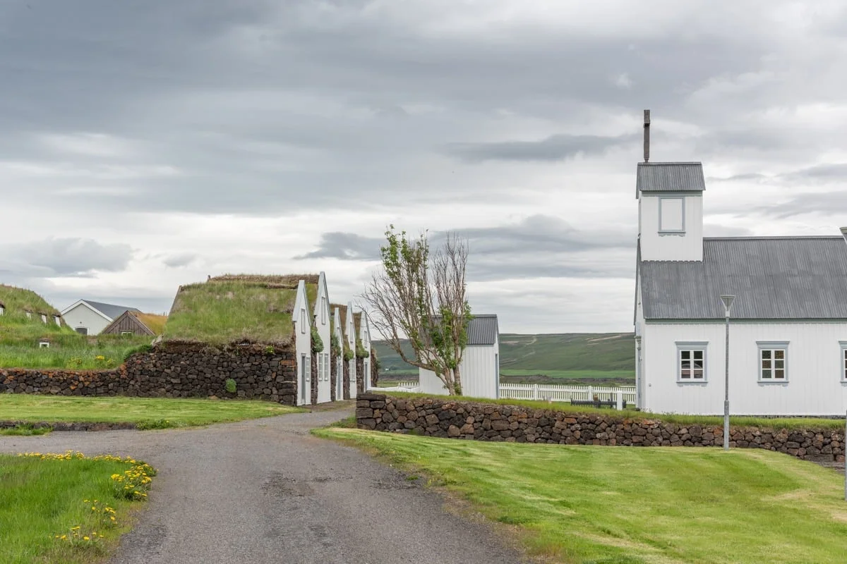 Église blanche et maisons en tourbe bordant un chemin herbeux