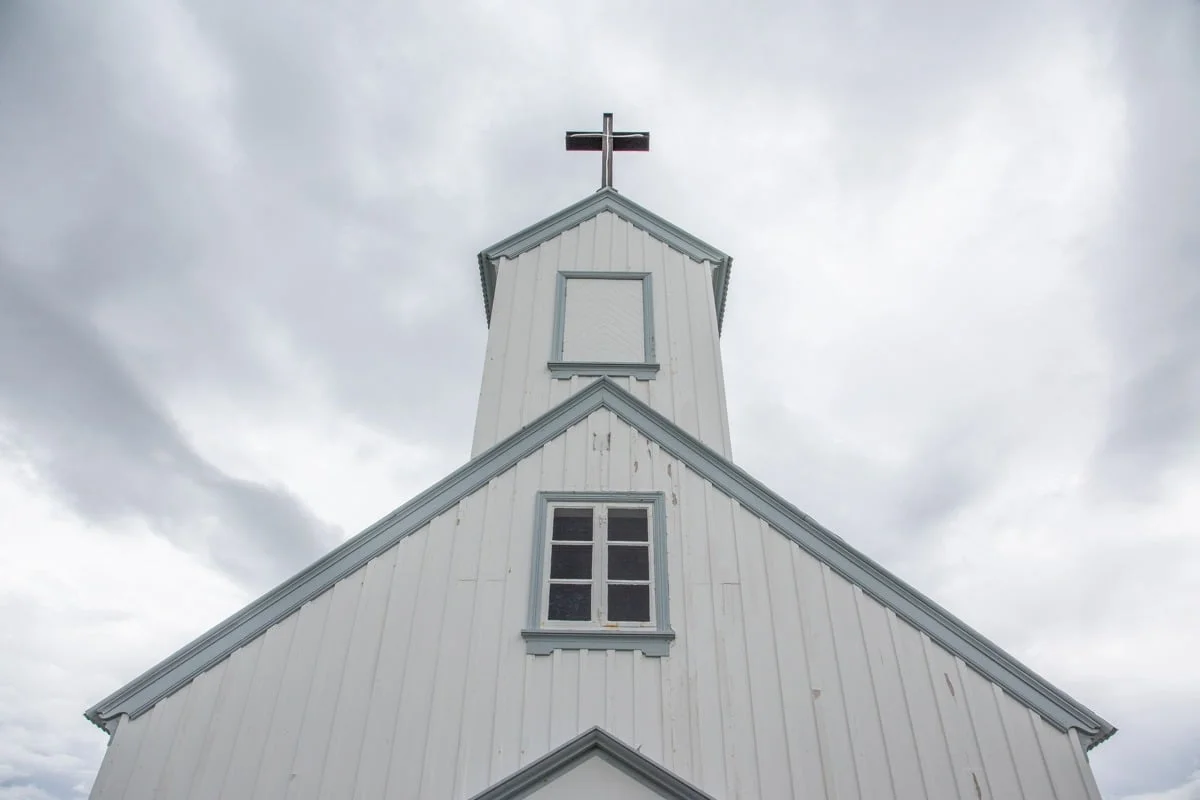 Façade d'une petite église en bois blanc surmontée d'une croix