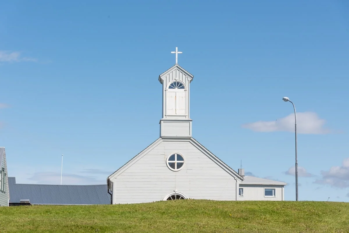 Eglise blanche avec clocher et croix sous ciel bleu