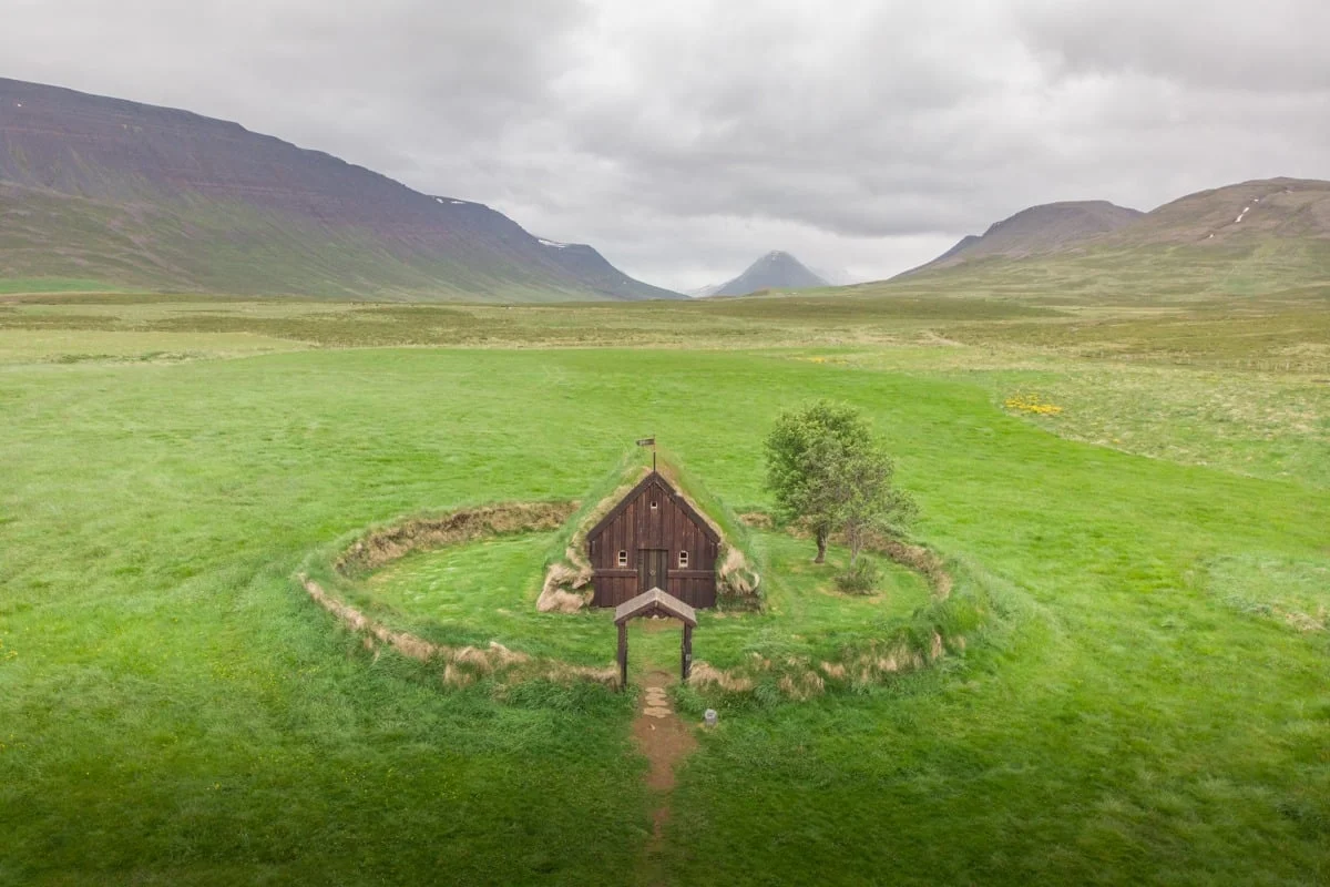Petite église entourée d'une prairie verte et de montagnes