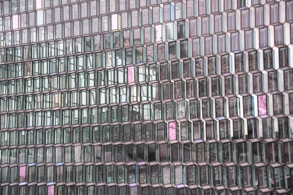 Façade géométrique en verre aux reflets roses et bleus