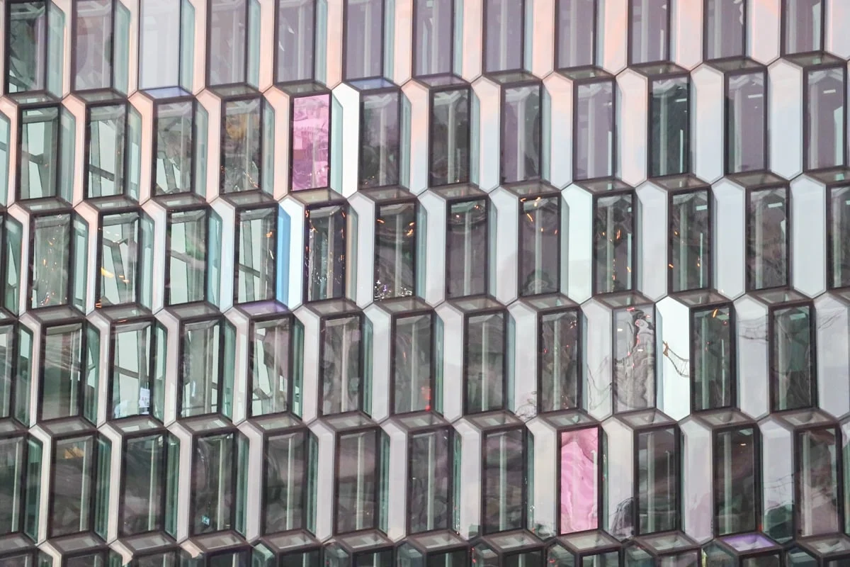 Façade géométrique en verre avec panneaux hexagonaux aux reflets colorés