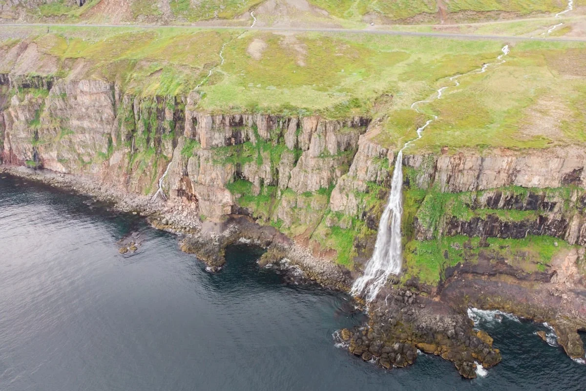 Falaise et cascade se jetant dans un fjord, vus depuis un drone