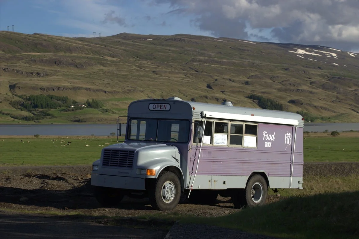 Bus américain converti en food truck violet garé dans un paysage verdoyant
