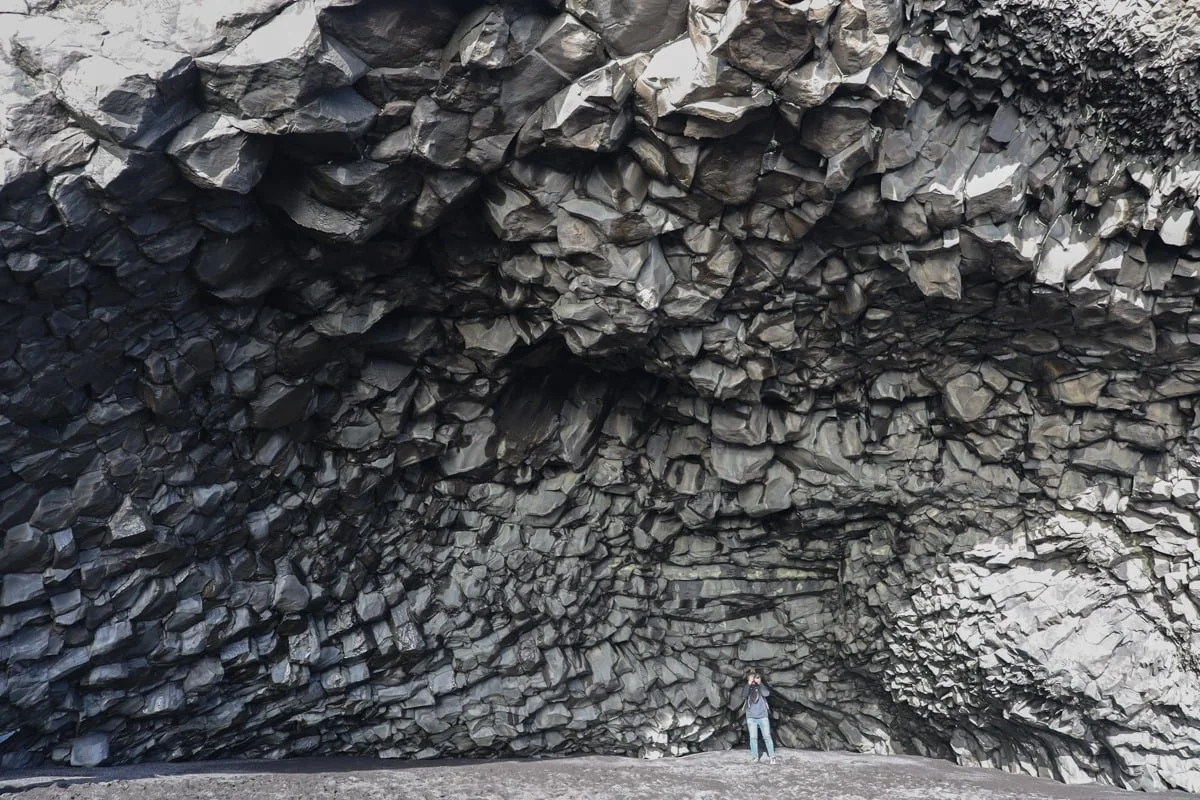 Personne sous une grotte de colonnes basaltiques noires