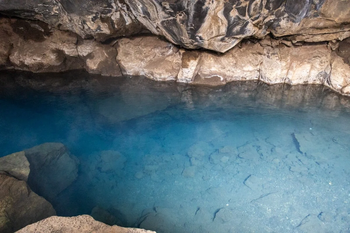 Piscine naturelle d'eau bleue translucide dans une grotte de lave