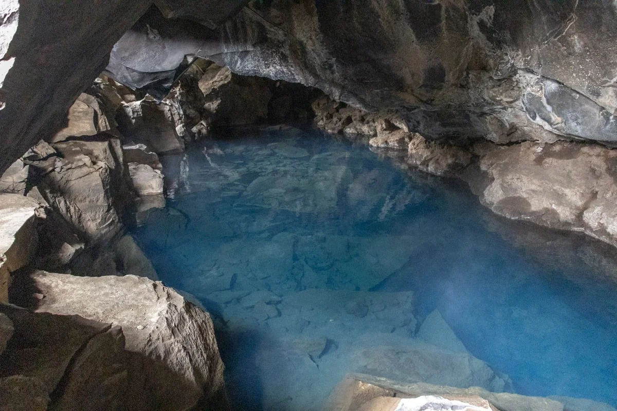 Source d'eau chaude turquoise dans une grotte de lave sombre