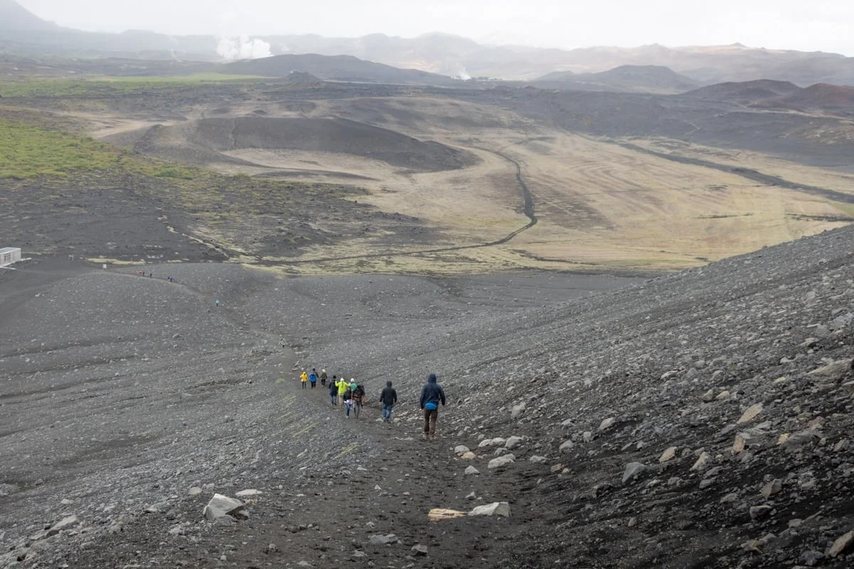 Groupe de randonneurs en file descendant un flanc volcanique sombre