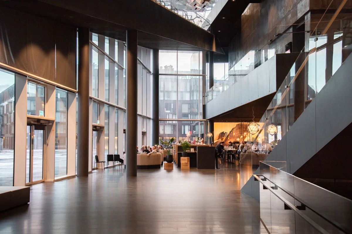 Hall d'entrée moderne avec grande verrière et restaurant au fond