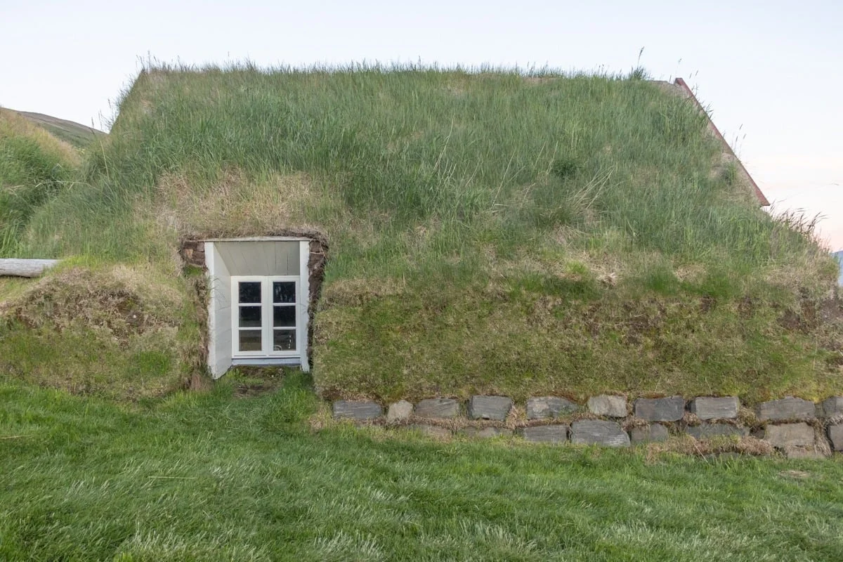 Maison traditionnelle au toit recouvert de gazon et fenêtre blanche