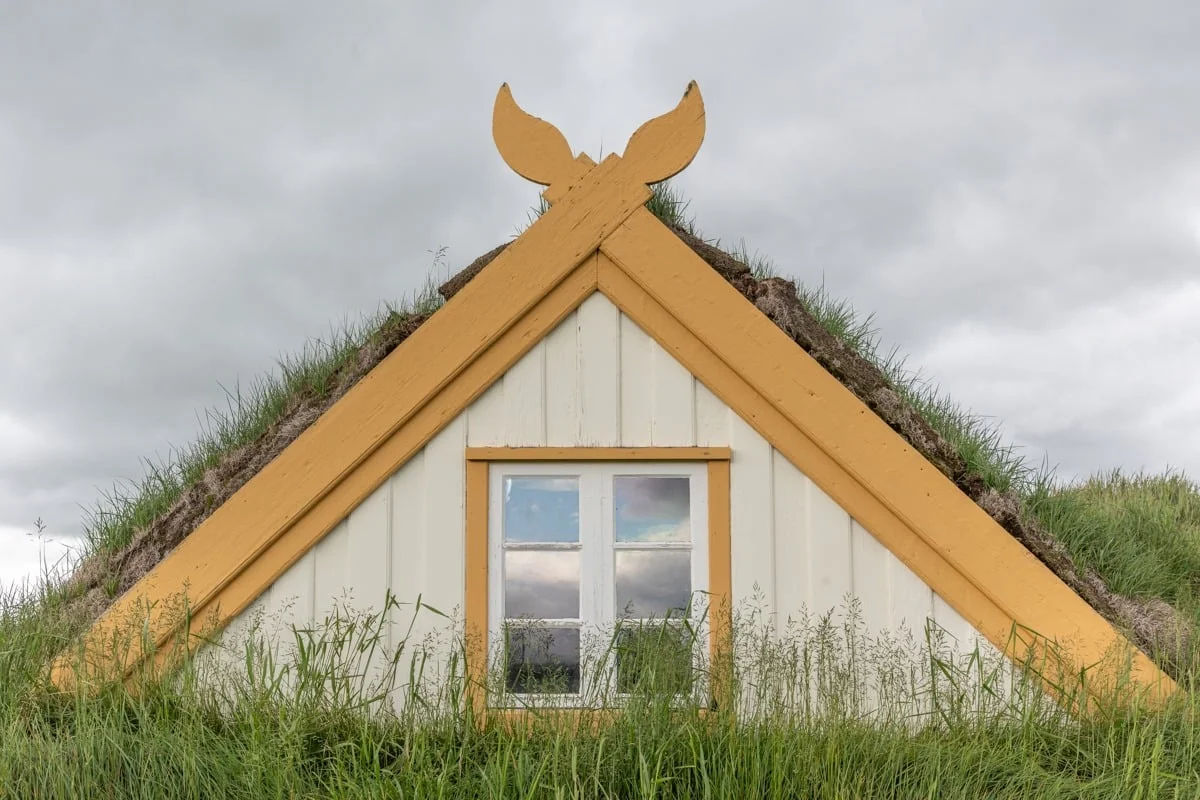 Façade de maison en tourbe avec toit herbeux et boiseries jaunes