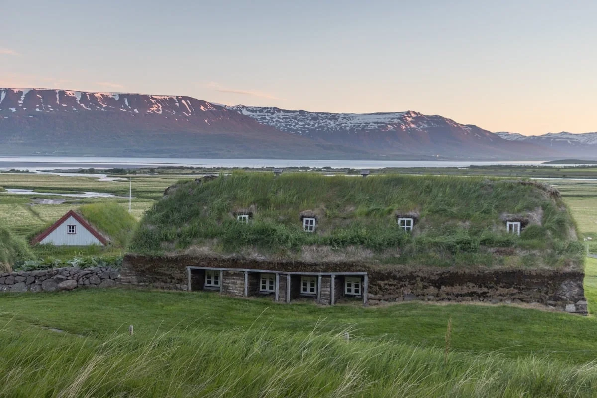 Maison traditionnelle en tourbe avec toit végétalisé, montagne enneigée en arrière-plan