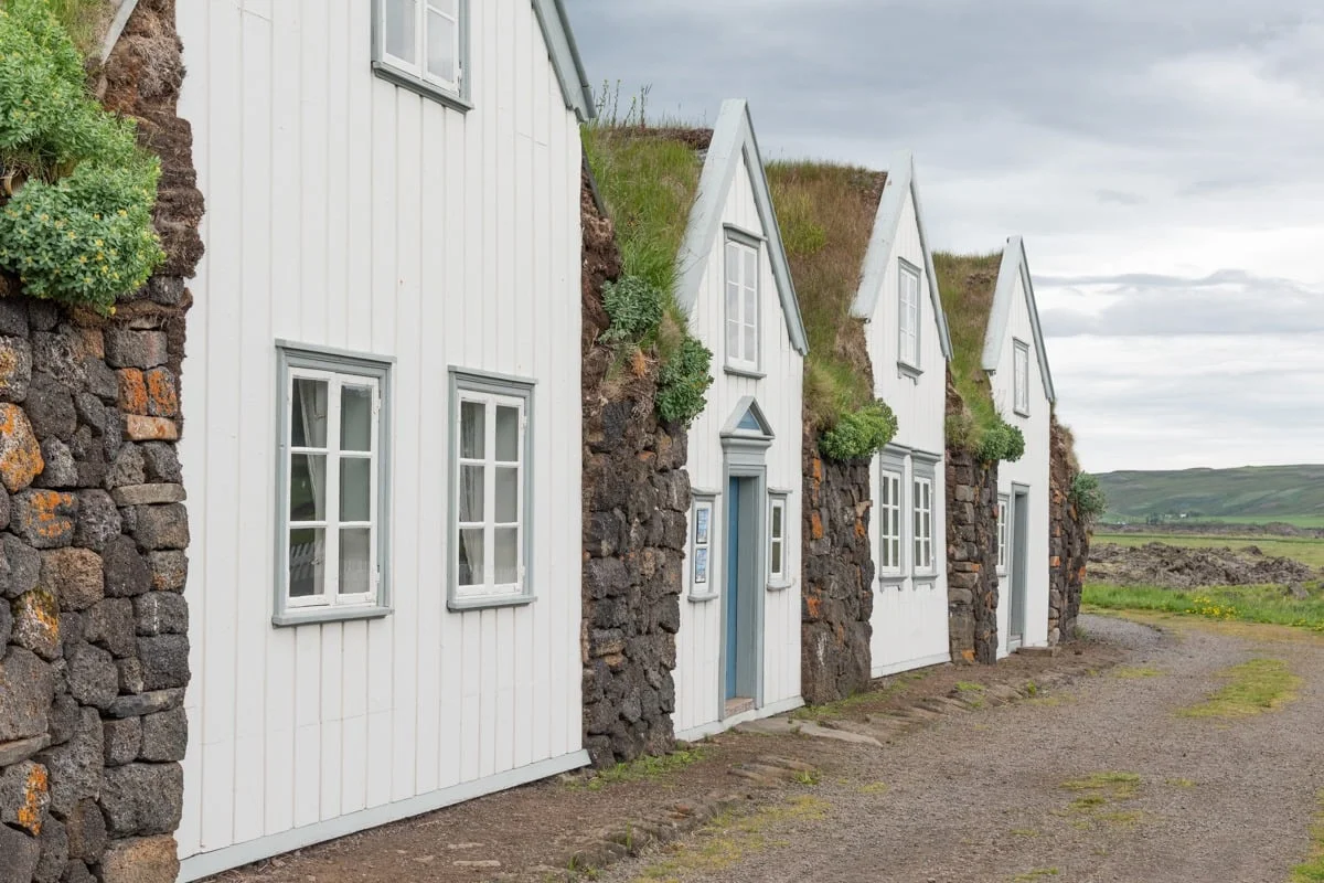 Rangée de maisons blanches en pierre avec toits en tourbe verte
