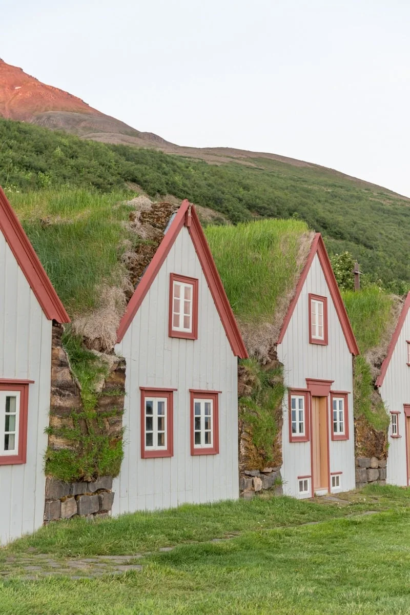 Rangée de maisons blanches aux toits de tourbe verts et encadrements rouges