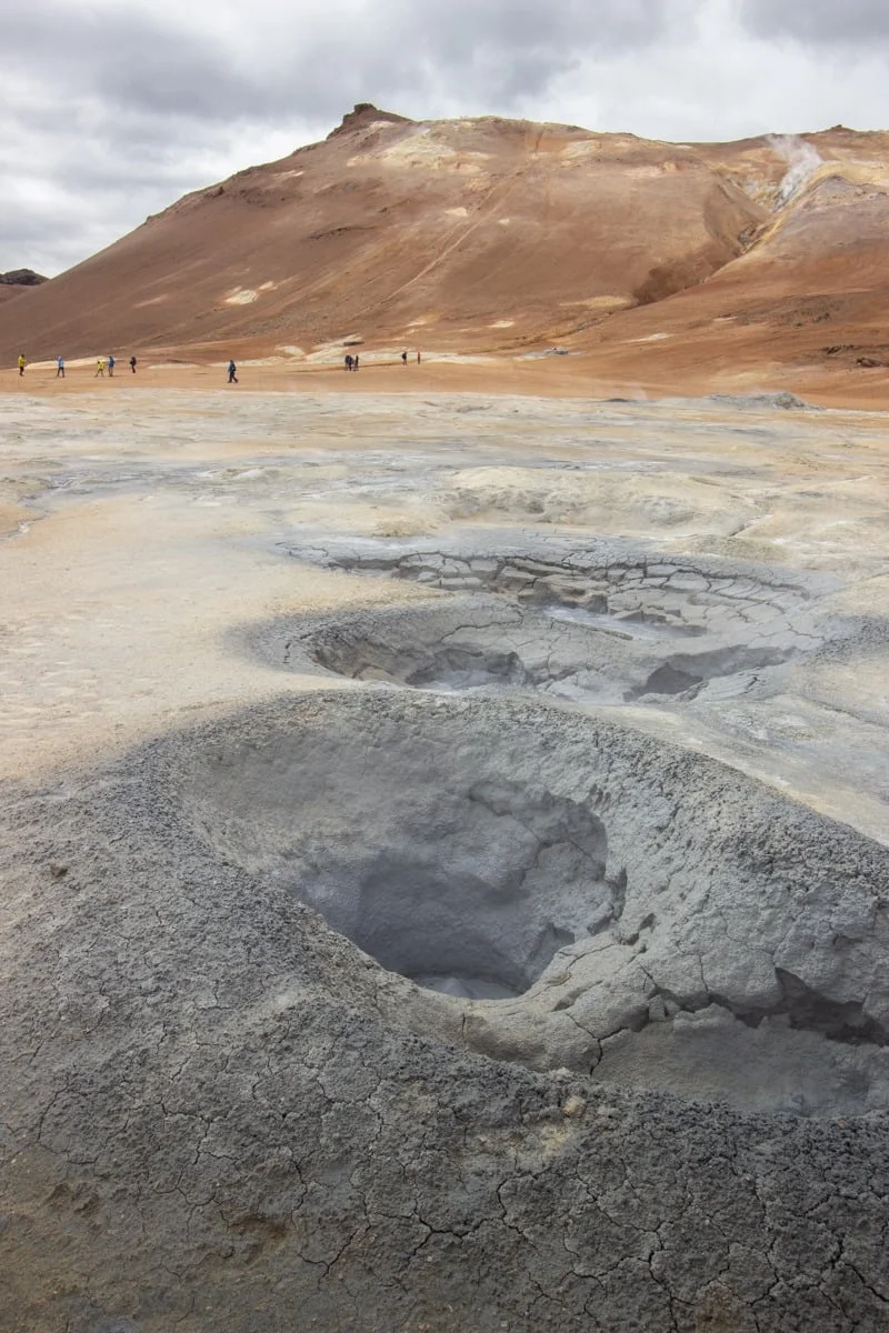 Mares de boue bouillonnante au pied d'une colline volcanique ocre