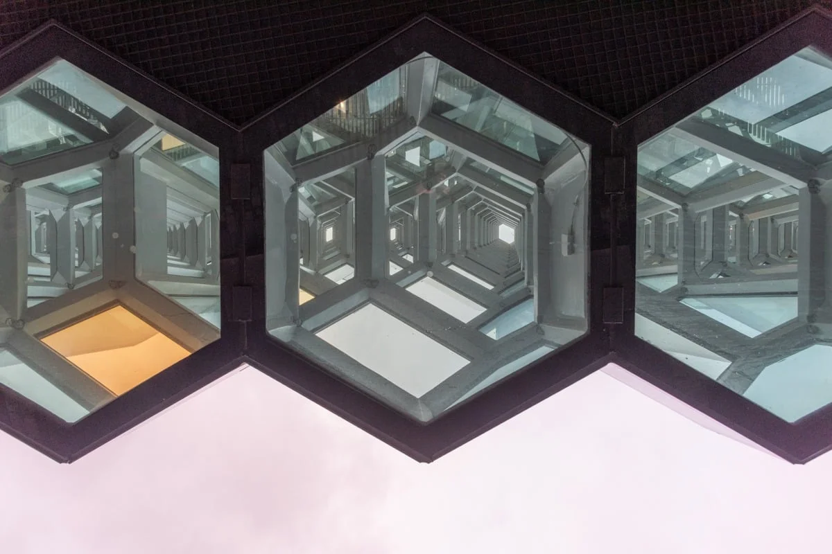 Trois panneaux hexagonaux en verre créant un effet de tunnel infini