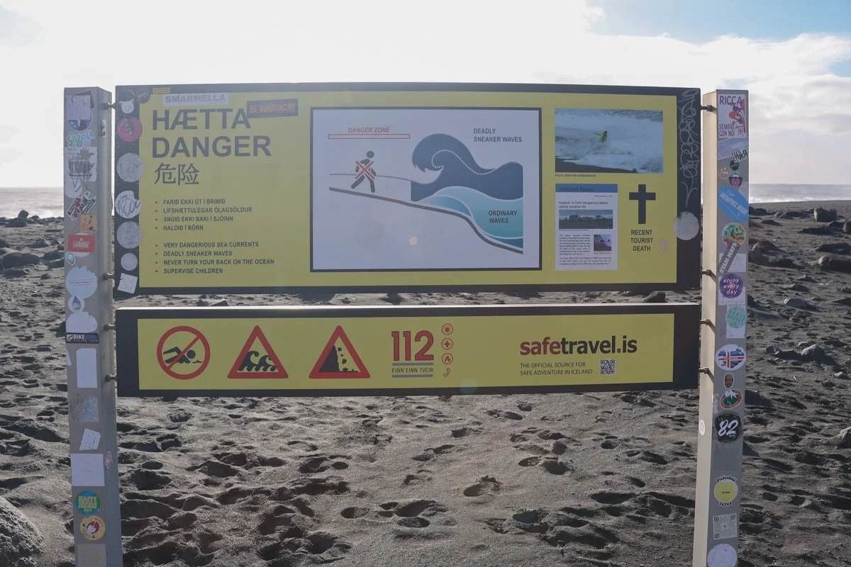 Panneau d'avertissement danger vagues sur plage de sable noir